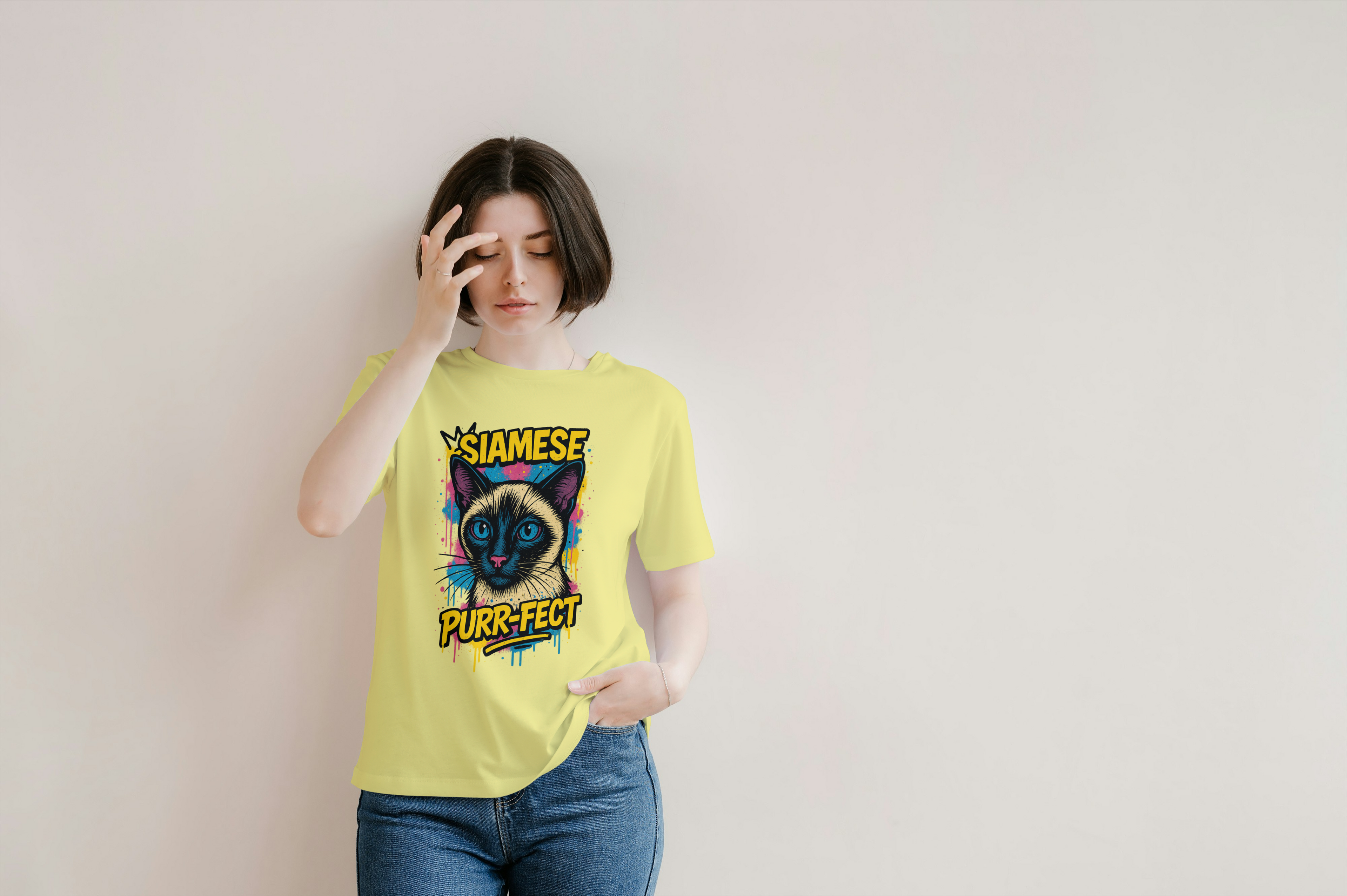 Woman wearing yellow Siamese cat t-shirt with graffiti-style PURR-FECT design on neutral background

